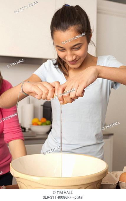 girl , breaking an egg in kitchen