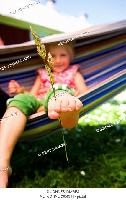 A girl with a straw of grass between her toes