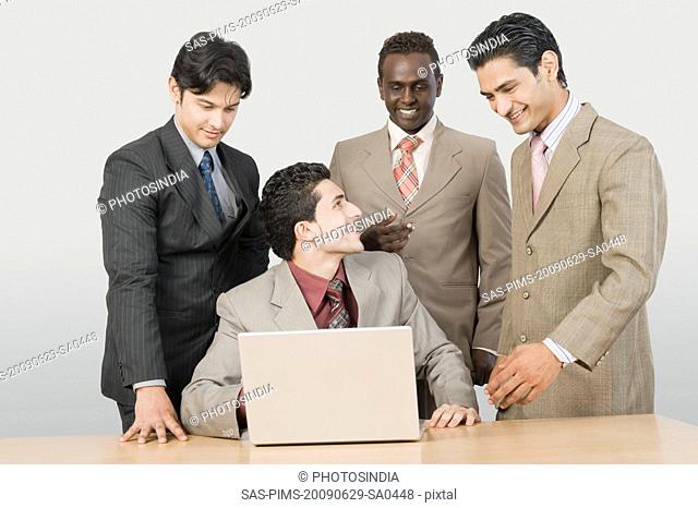 Four businessmen in front of a laptop