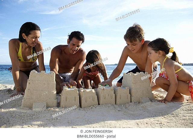 Hispanic family building sand castle