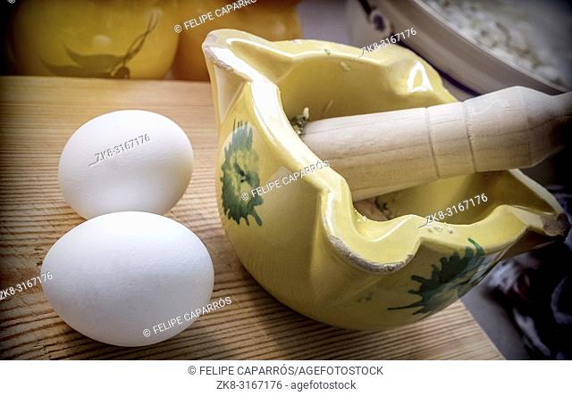 Traditional ceramic mortar with two white hen eggs in a kitchen, traditional cooking utensils