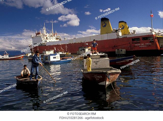 Patagonia, Chile, Pacific Ocean, Fishermen bringing their boats to be anchored in the harbor as a passenger/cargo ferry boat is docked in Puerto Natales in...