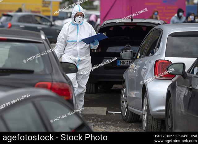 27 October 2020, Hessen, Marburg: Dressed in a full-body protective suit is an employee of a Corona test centre at the Marburg exhibition centre