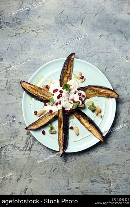 Baked eggplant served with yogurt and pomegranate seeds