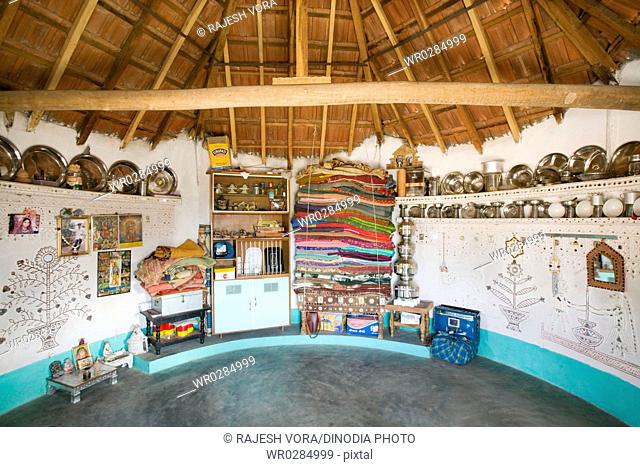 Interior of bhunga circular house with household utilities placed at decorated circular walls , Kutch , Gujarat , India