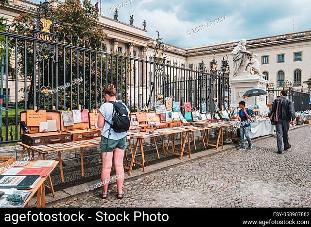 Berlin, Germany - May, 2019: Person looking at second hand books for sale on flea market in front of the Humboldt University in Berlin, Germany