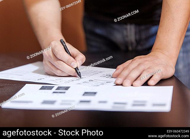 The designer in working process, at a table does sketches by a pencil