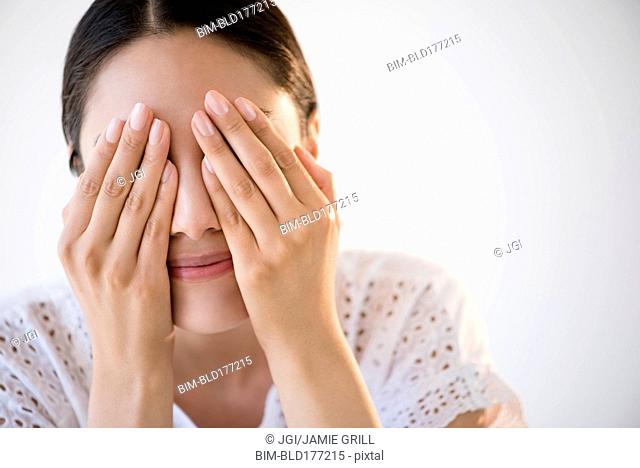 Hispanic woman covering her eyes