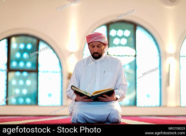 muslim man praying Allah alone inside the mosque and reading islamic holly book quran