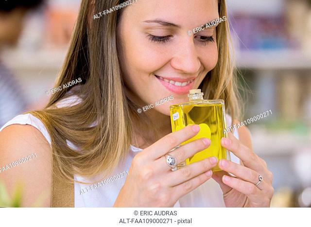 Young woman smelling perfume in shop