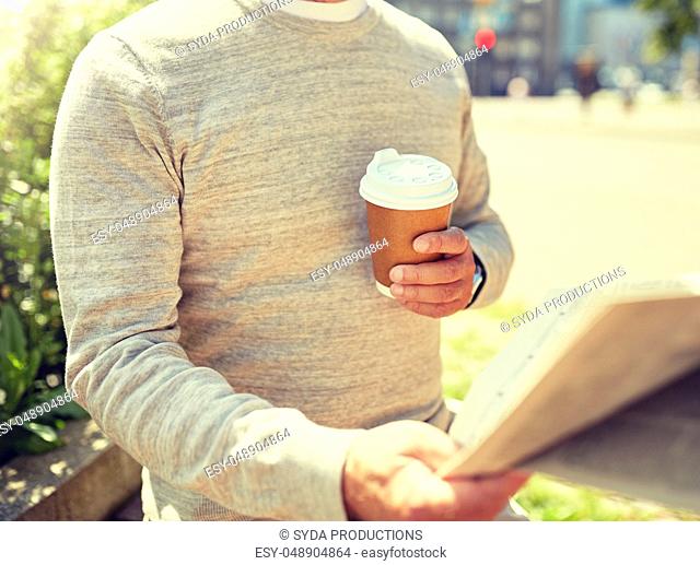senior man with coffee reading newspaper outdoors