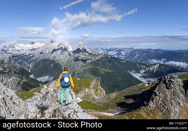 Hiker on a summit, Westliche Törlspitze, mountains in dramatic clouds, Zugspitze in the back, Wetterstein Mountains, Garmisch-Partenkirchen, Bavaria, Germany