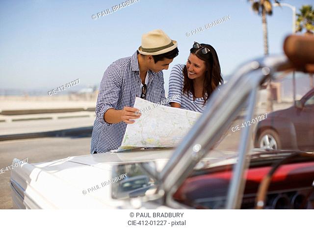 Couple reading road map on convertible
