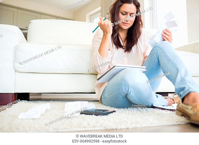 Young woman getting stressed over bills on floor of living room