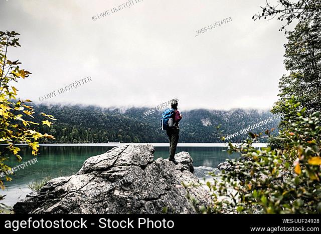 Female backpacker standing on rock by lake
