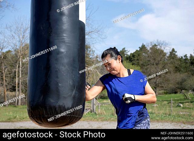 Woman training with boxing bag in outdoor gym