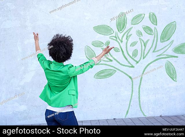 Woman presenting painted tree on wall