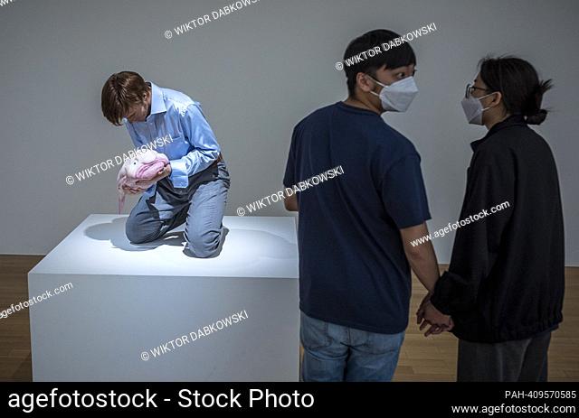 People look at Eulogy a sculpture of nicely dressed man with blowfish in his hands by Patricia Piccinini during the SUPERNATURAL: Sculptural Visions of the Body...