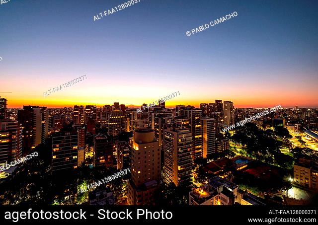 Aerial view of crowded cityscape with high rise buildings at dusk