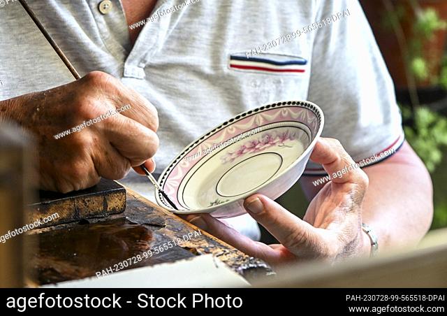 25 de julio de 2023, Berlín: Un pintor de porcelana trabaja en una placa de Kurland en el Königliche Porzellan-Manufaktur Berlin