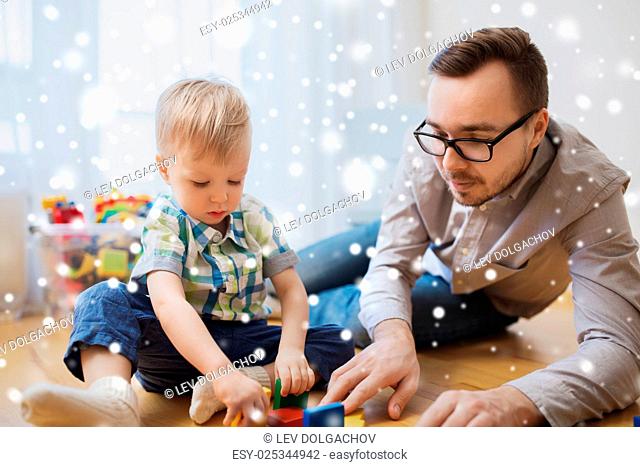family, childhood, creativity, activity and people concept - happy father and little son playing with toy blocks at home over snow