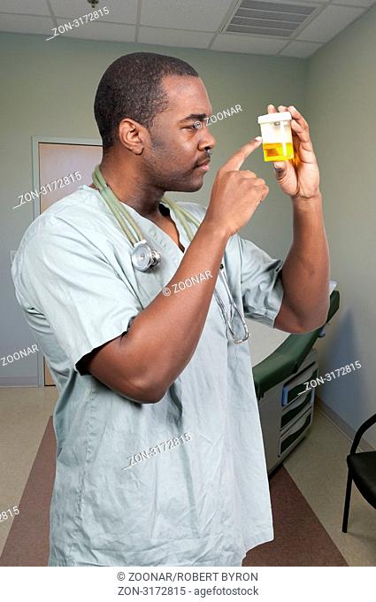 Young black African American man doctor in scrubs holding a urine sample