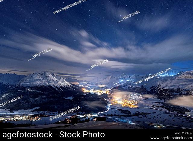 Starry winter sky over St. Moritz village and Upper Engadine covered with snow viewed from Muottas Muragl, Graubunden, Switzerland, Europe