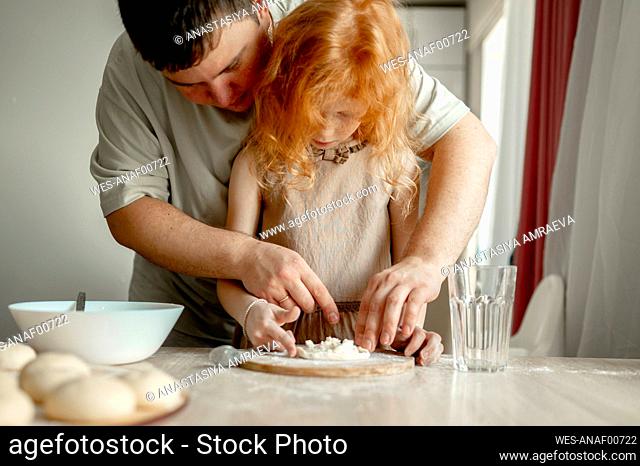 Father teaching daughter to prepare cheesecake at home
