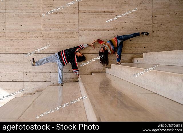 Couple of dancers on a wall, lifting the legs