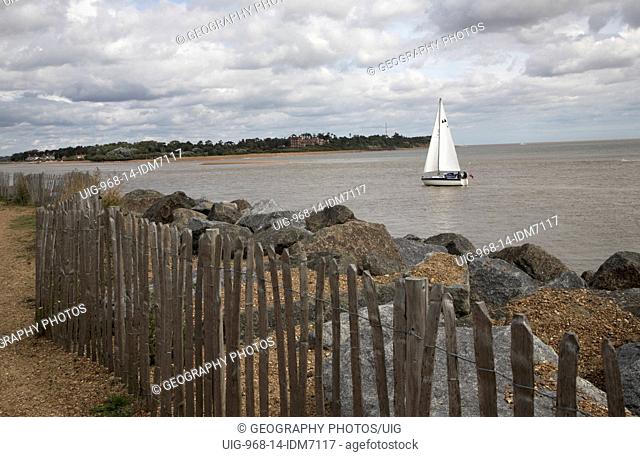 Mouth of the River Deben with sailing boat and rock armour coastal defenses, Felixstowe, Suffolk, England