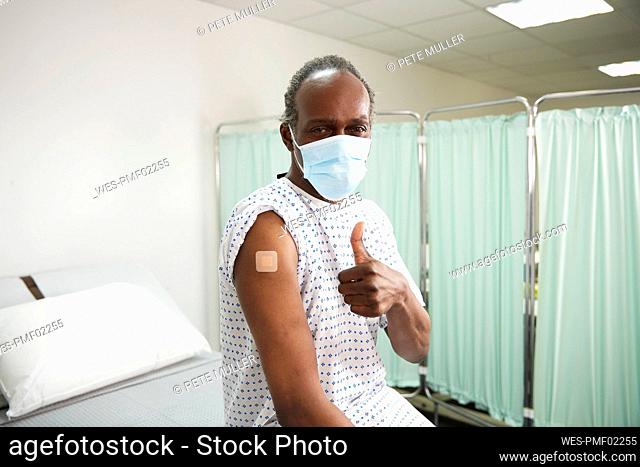 Patient with vaccinated arm showing thumbs up gesture in medical room
