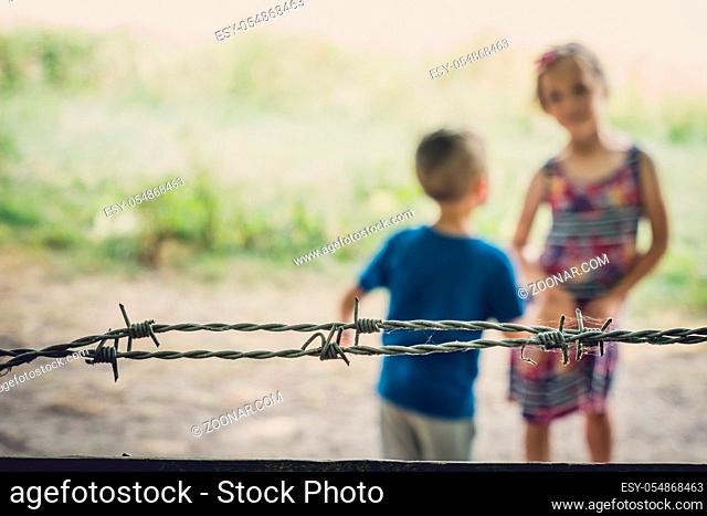 Brother and sister playing behind the barbed wired fence gates to the Banstead woods in Surrey, England