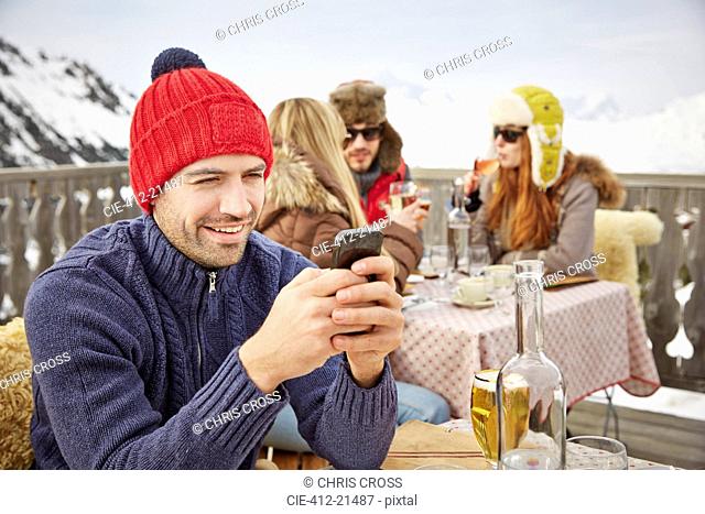 Man using cell phone on snowy balcony