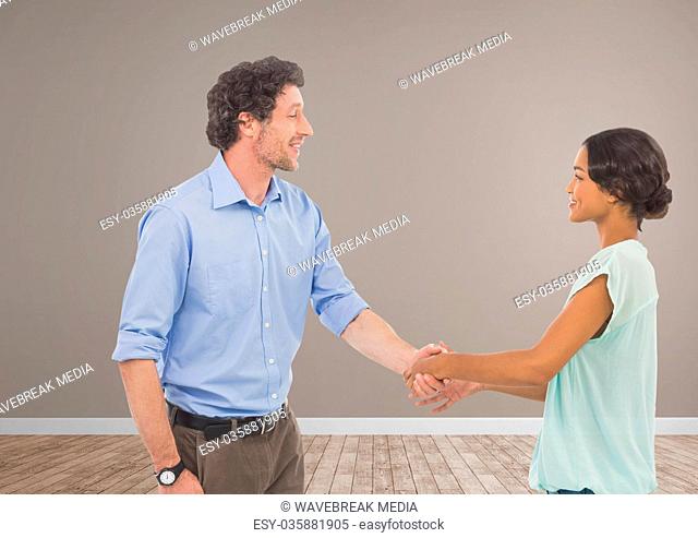 Man and woman shaking hands in brown room
