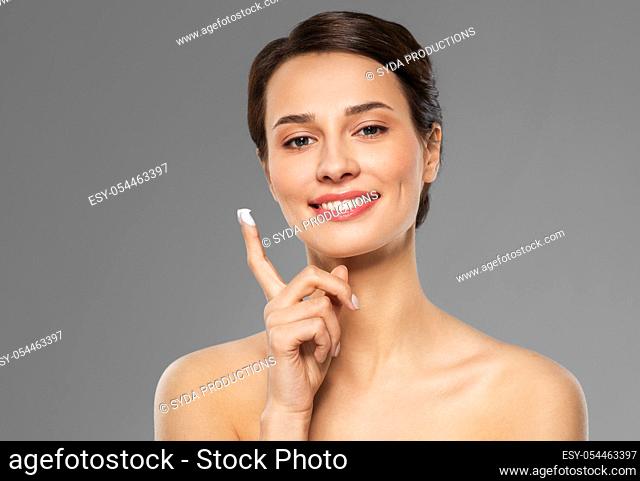 young woman with moisturizing cream on finger