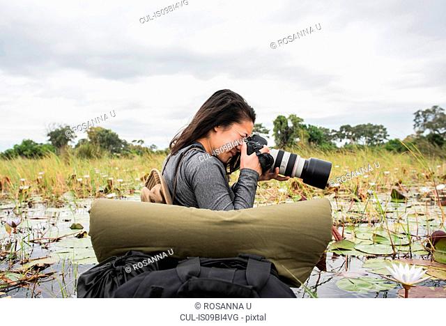 Young female tourist photographing Okavango Delta, Botswana, Africa