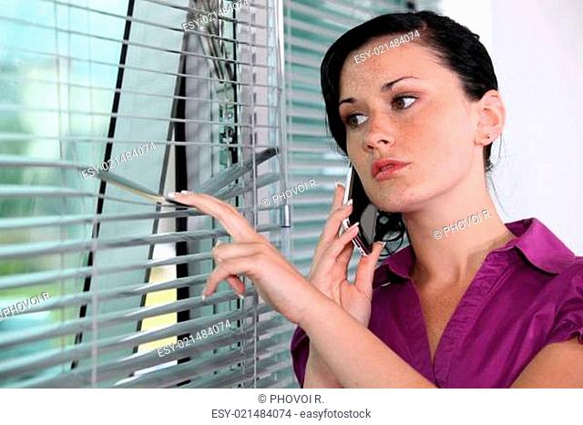 Woman peeking though window blinds