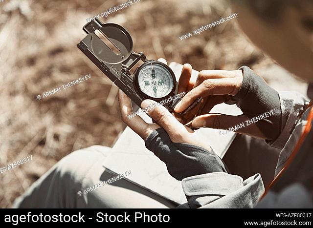 Woman using compass during sunny day