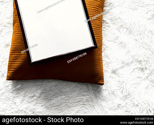 Black thin wooden frame with blank copyspace as poster photo print mockup, golden cushion pillow and fluffy white blanket, flat lay background and art product
