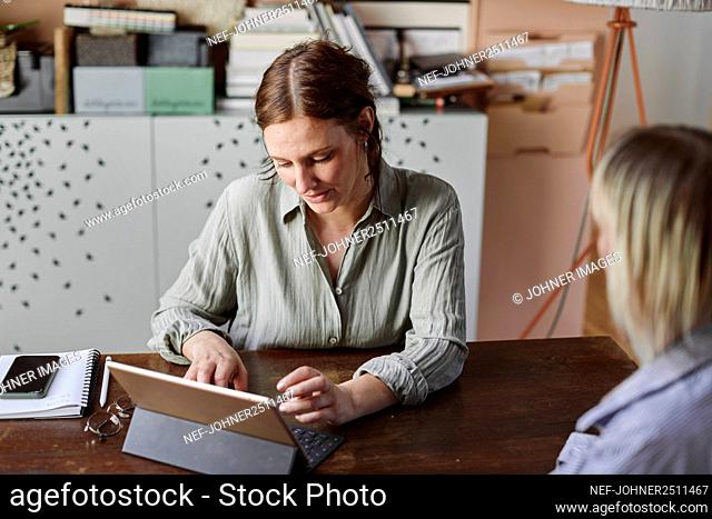 Women sitting at desk and using tablet