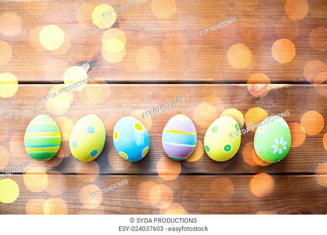 easter, holidays, tradition and object concept - close up of colored easter eggs on wooden surface with copy space