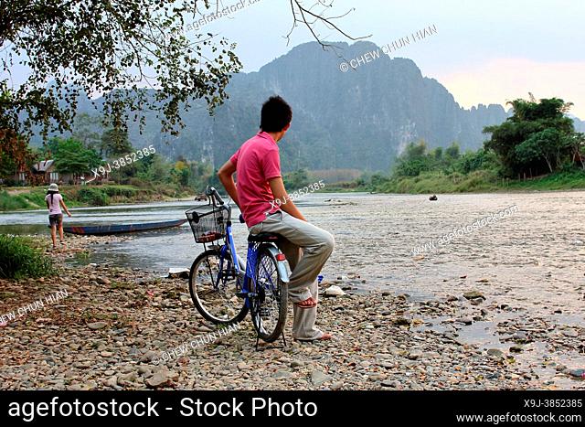 Tourists relax by the Nam Song river at sunset in Vang Vieng, Laos