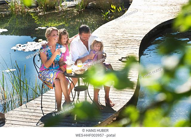 Austria, Salzburg County, Family having breakfast on bridge over pond