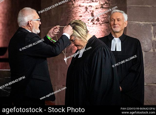 10 April 2022, Baden-Wuerttemberg, Karlsruhe: Heike Springhart (center), the new bishop of Baden, receives the pectoral from synod president Axel Wermke (left)...