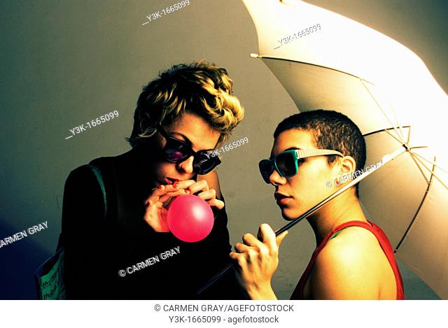 Studio picture of two girls playing with a ballon and an umbrella