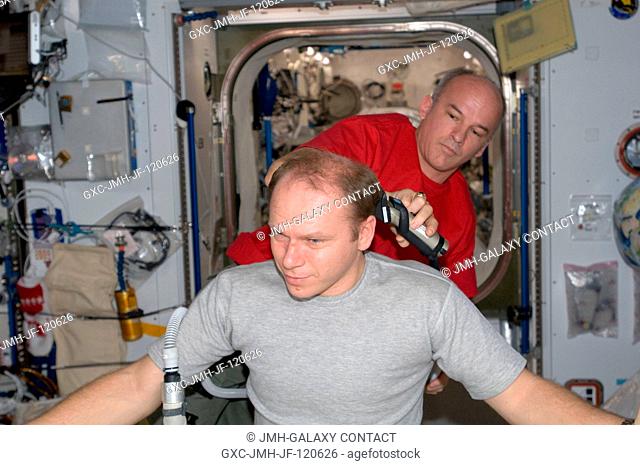 NASA astronaut Jeffrey Williams, Expedition 22 commander, trims Russian cosmonaut Oleg Kotov's hair in the Harmony node of the International Space Station