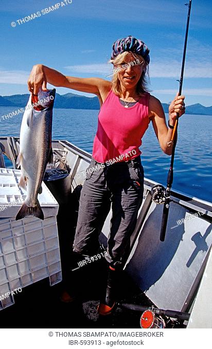 Woman catches a Coho or Silver Salmon (Oncorhynchus kisutch) in Prince William Sound, Alaska, USA