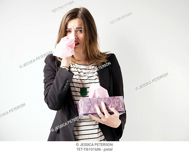 Studio shot of young woman sneezing