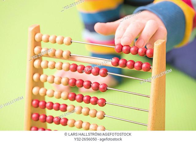 Child hand counting on abacus. Concept of childhood learning, mathematics and early education