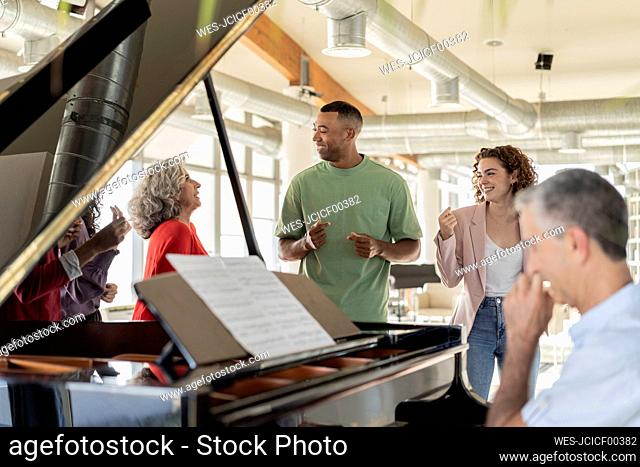 Businessman looking at mature businesswoman singing in office